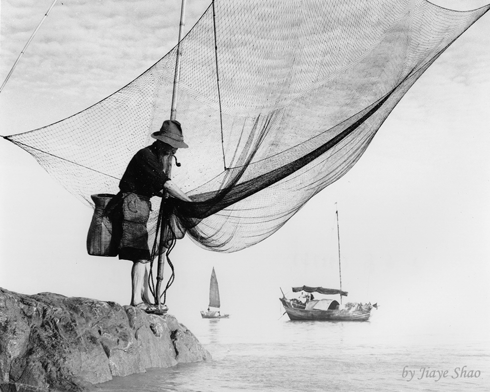 A fisherman standing by his net with a boat in the background